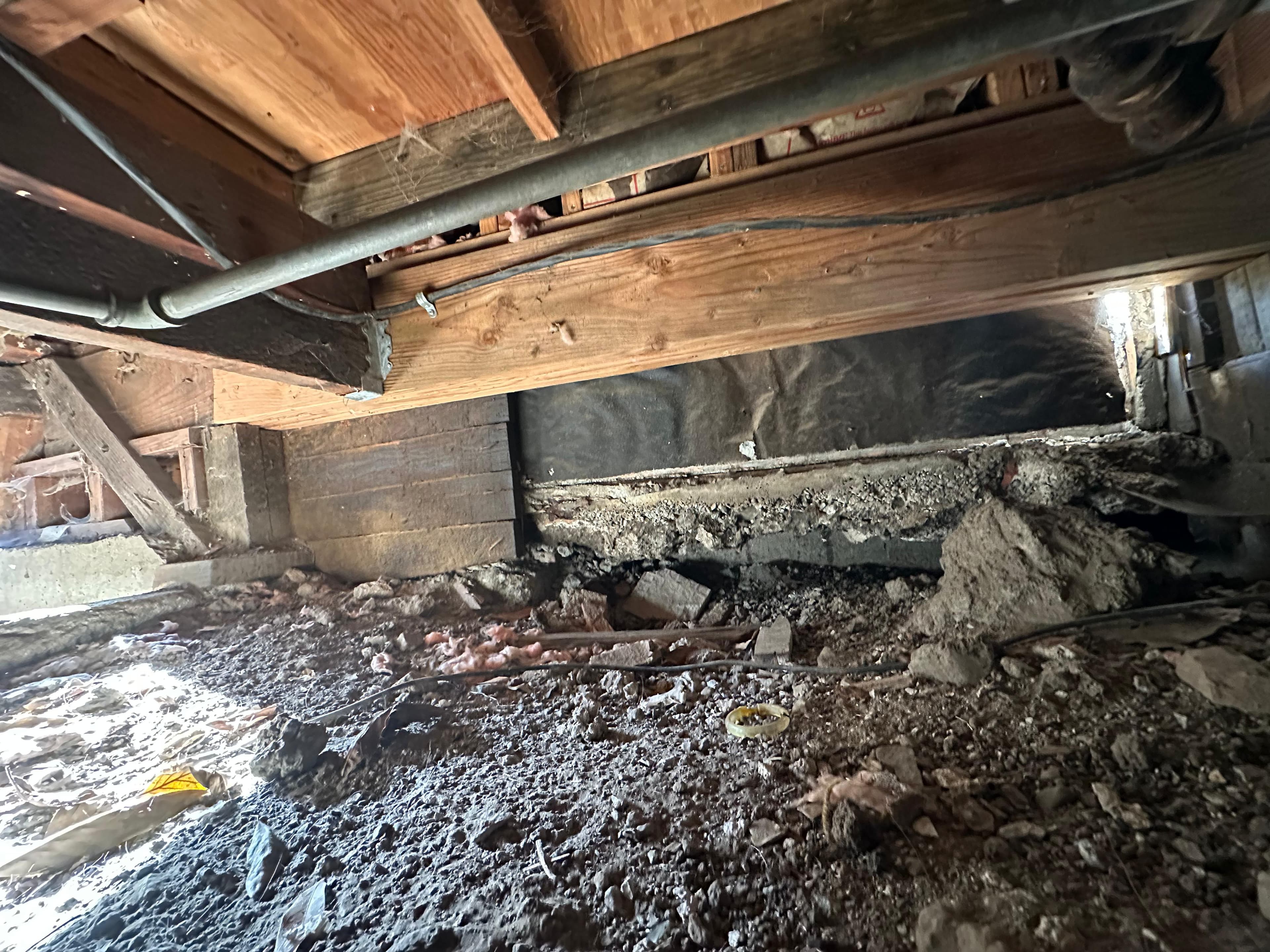 Deteriorated concrete support and debris in Oakland crawl space